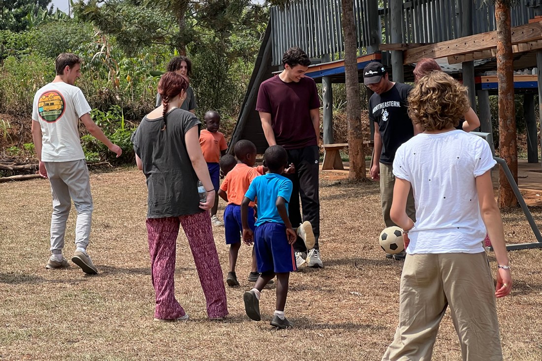 Participants in the Rwanda Dialogue kick a soccer ball with several Black Rwandan children.