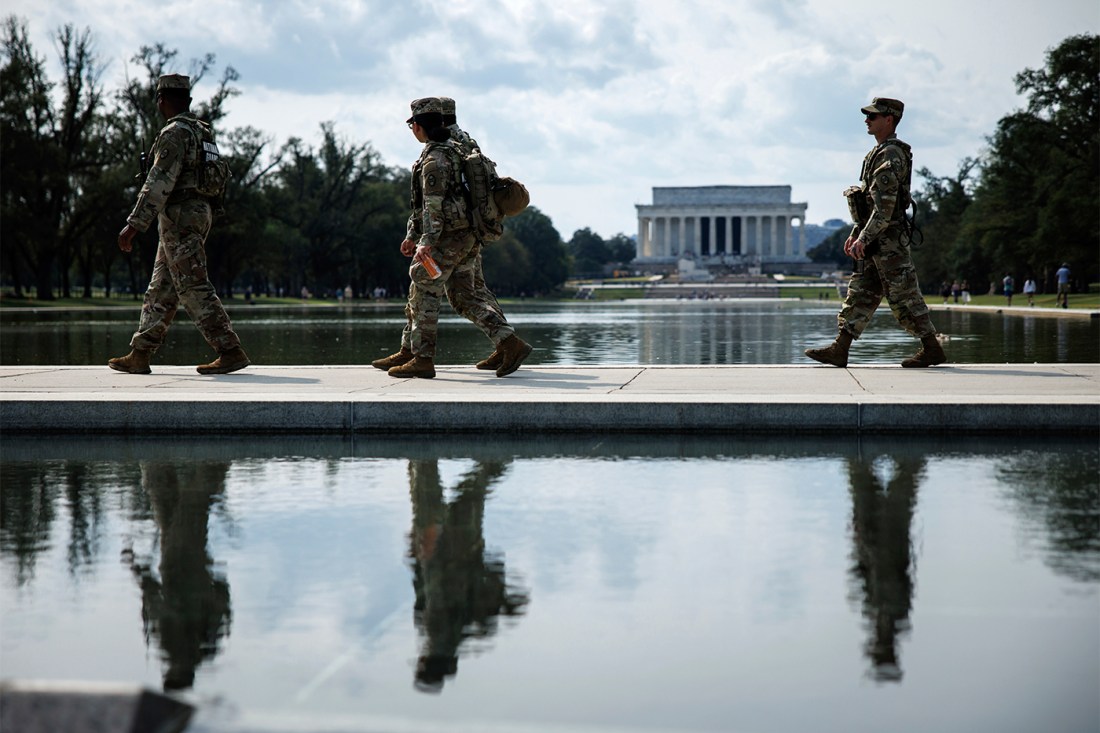 National Guardsmen depicted in front of the National Mall, walking by the Reflecting Pool.