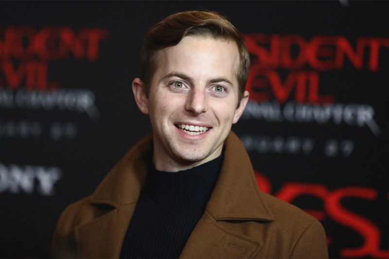 A portrait of Ned Fulmer, a white man, who is depicted in a brown coat and smiling.