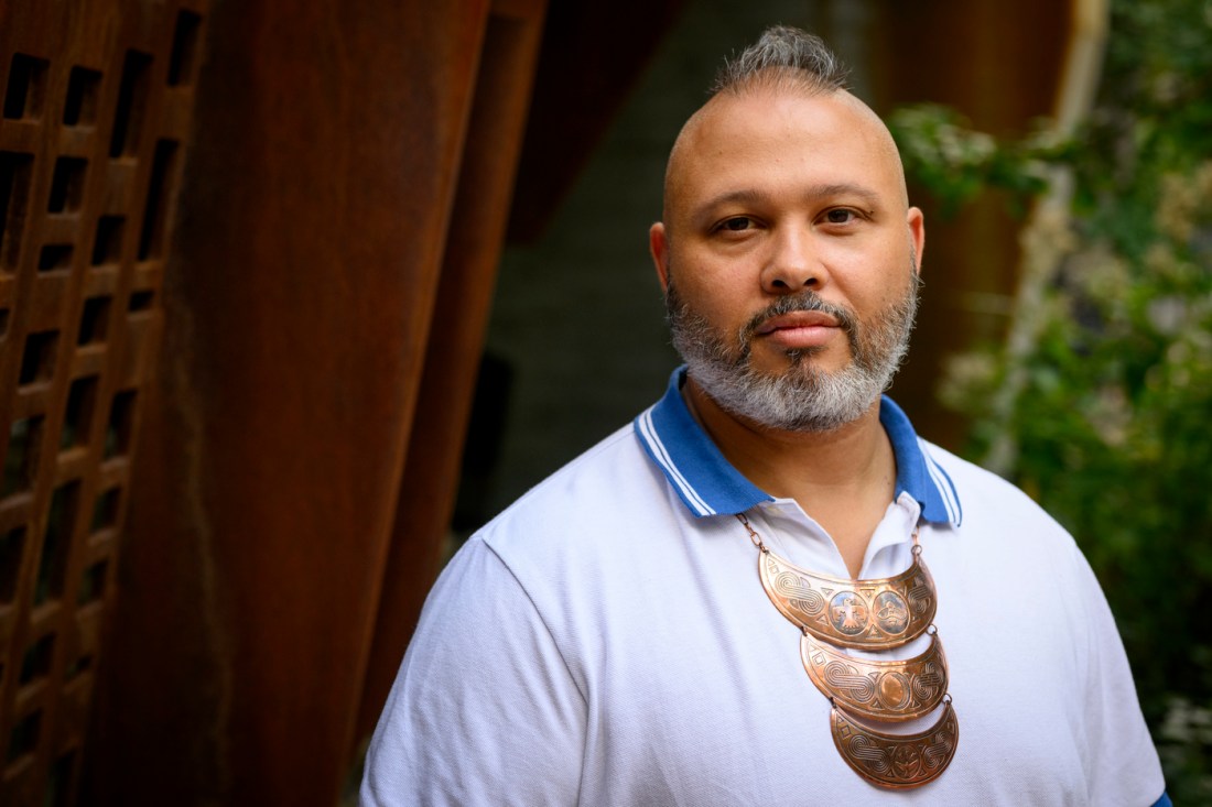 Portrait of Sebastian Ebarb wearing a blue polo shirt and a decorative necklace over top.
