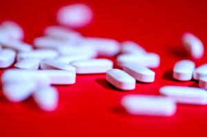 White Tylenol pills spread out on a red surface.