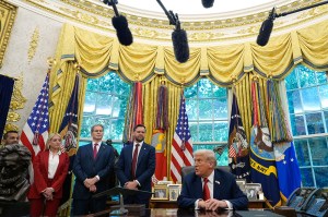 President Donald Trump and members of his cabinet in the Oval Office, as microphone equipment hangs overhead.