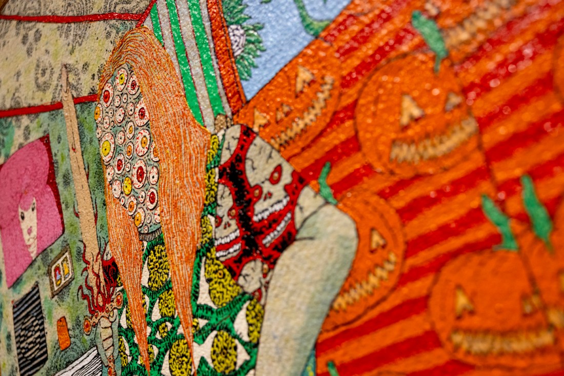 A close-up of a vibrant textile art featuring intricate embroidery, decorative patterns, and embellishments. 