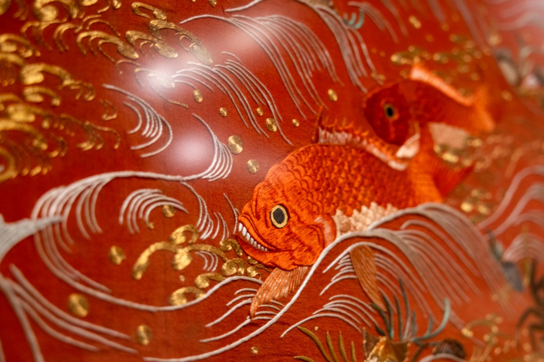 Close-up of a decorative red and gold koi fish with intricate wave patterns and metallic details from a piece of artwork.