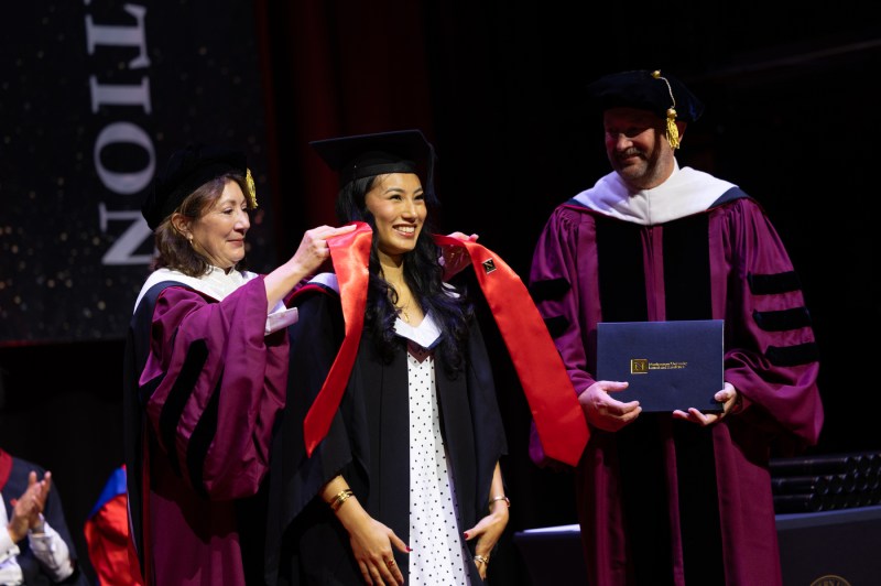 A person receives their graduation sash while standing on a stage.