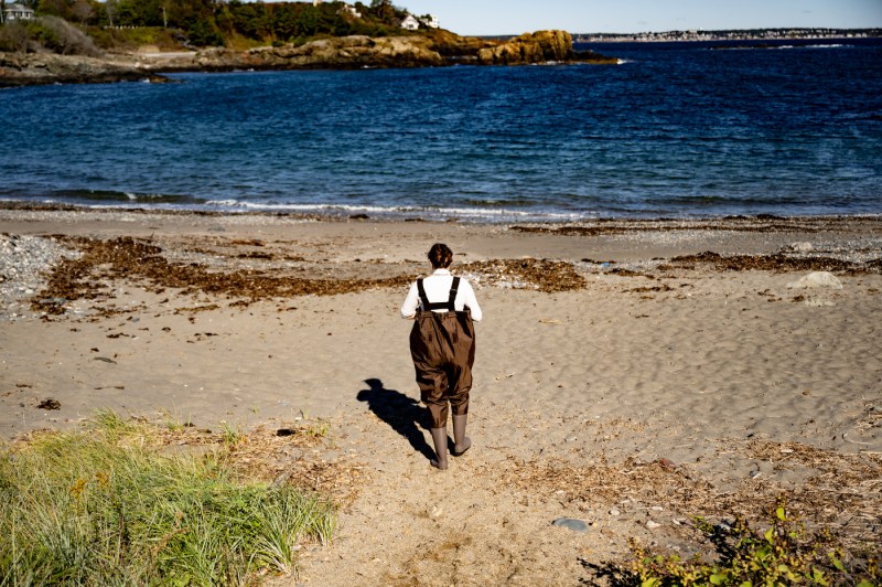 Graduate student Hannah Bray walks along Nahant Long Beach while collecting water samples to study pollution sources.
