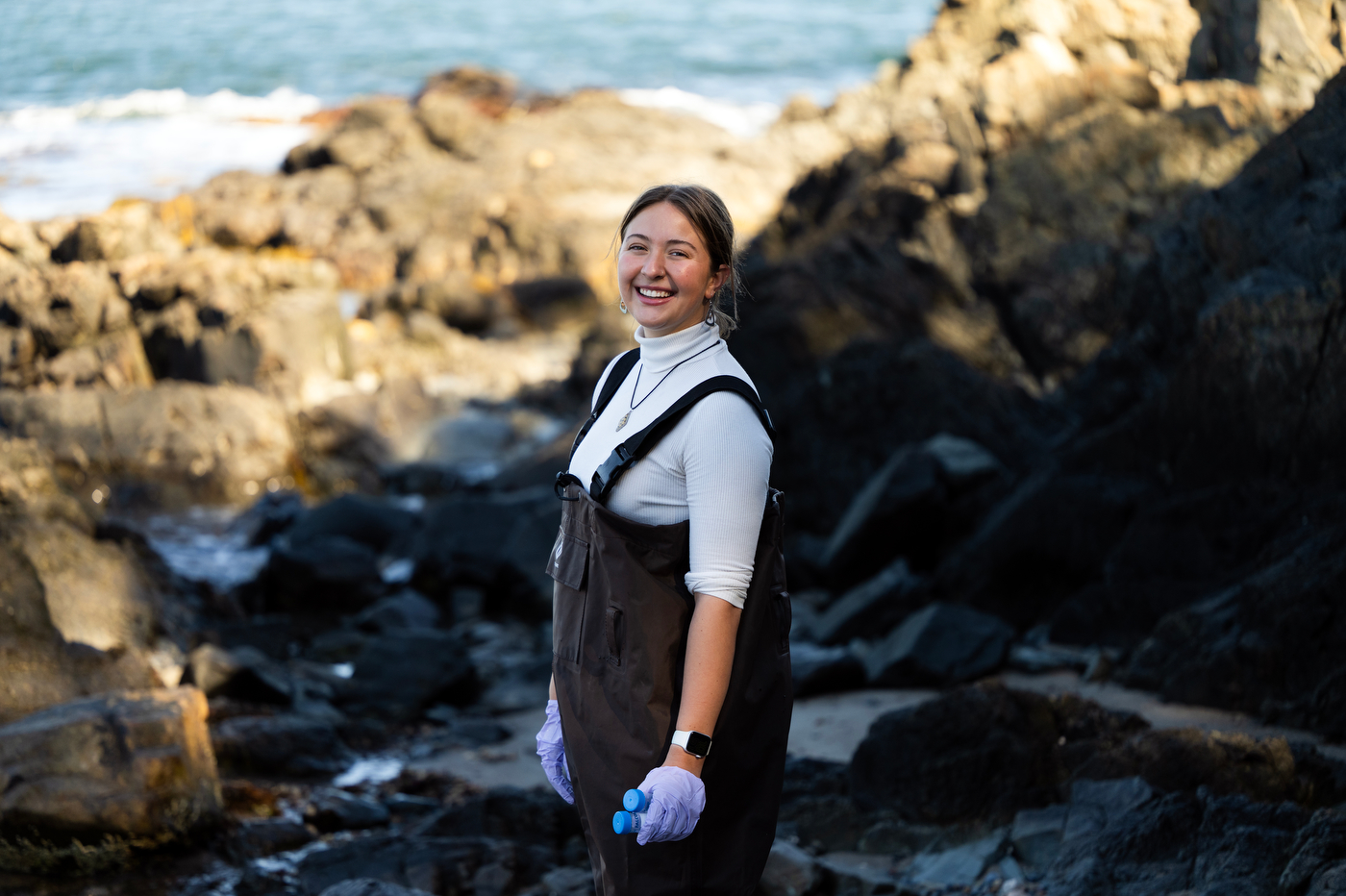 Grad student Hannah Bray poses among rocks on a beach.