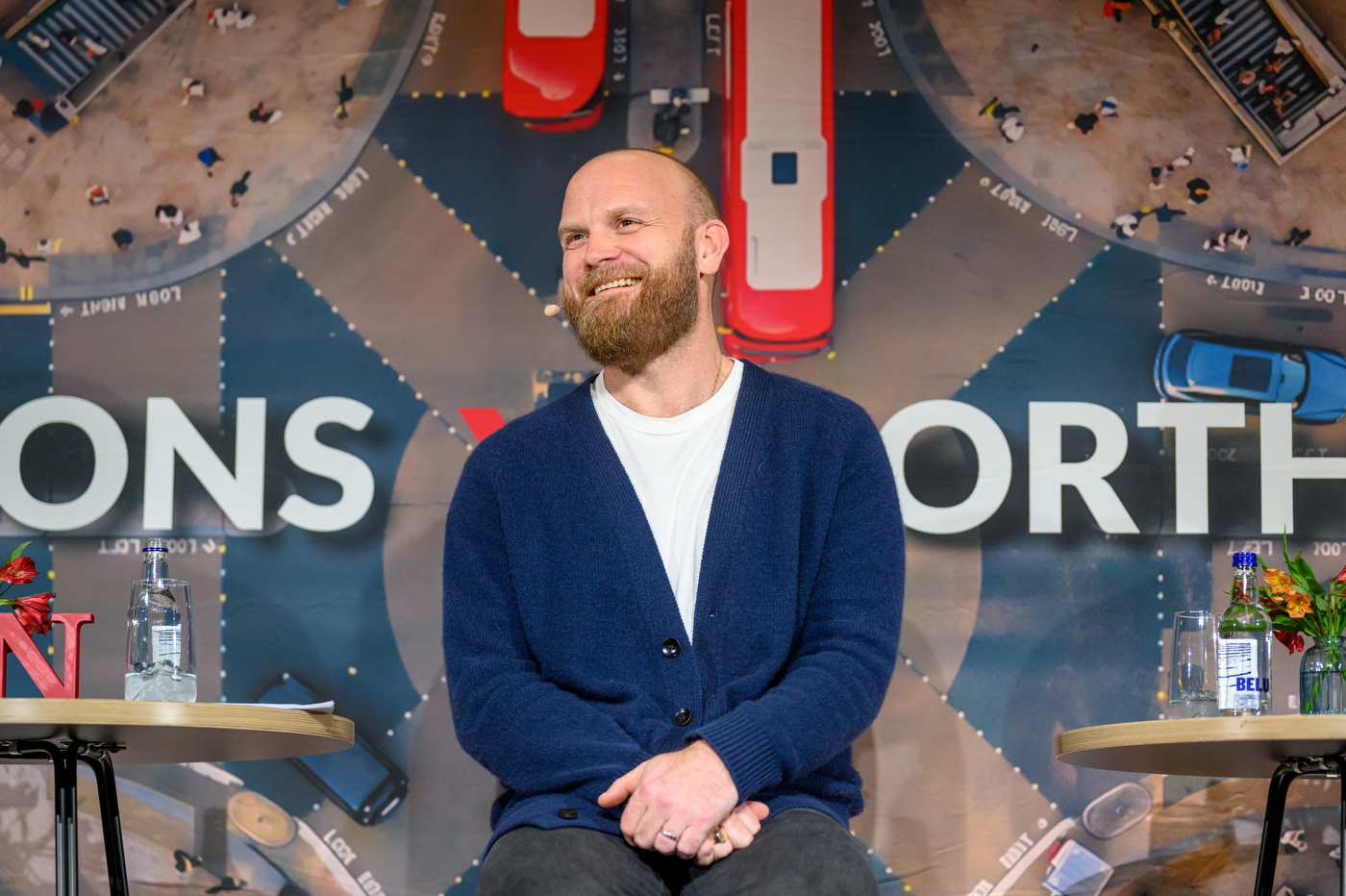 Will Champion sitting on stage at a panel discussion smiling.
