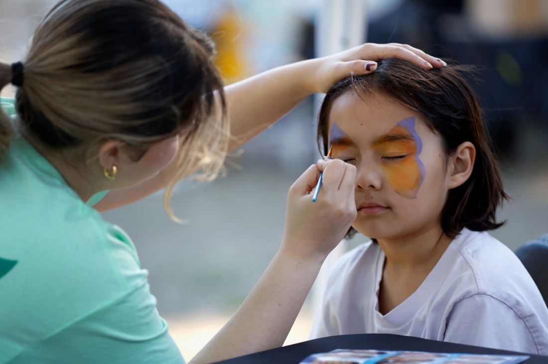 A child gets a purple and orange butterfly painted on their face at the Oakland Farm Festival.