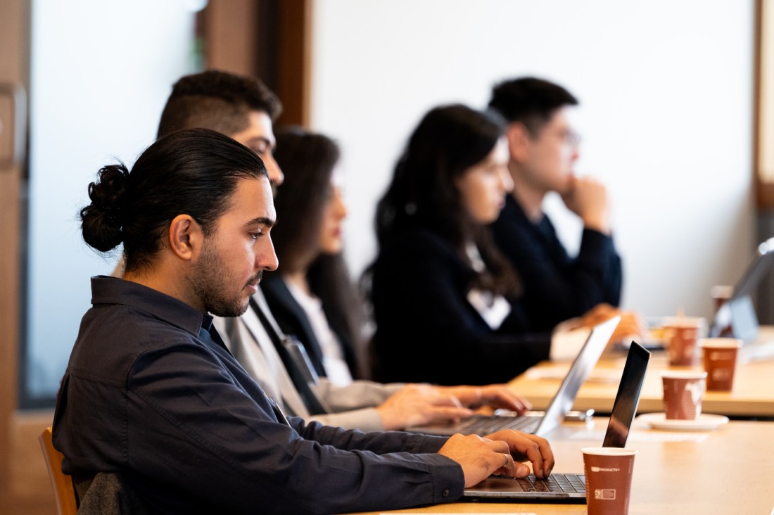 Attendees take notes and engage in discussion during the AI leadership panel at Northeastern University.