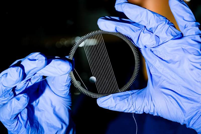 A close-up photo of someone wearing surgical gloves while holding a research tool.
