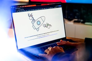 A person's hands typing on a laptop displaying a screen that shows Amazon Web Services page down.