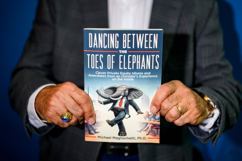 Mike Magliochetti holds up his book, "Dancing Between the Toes of Elephants."