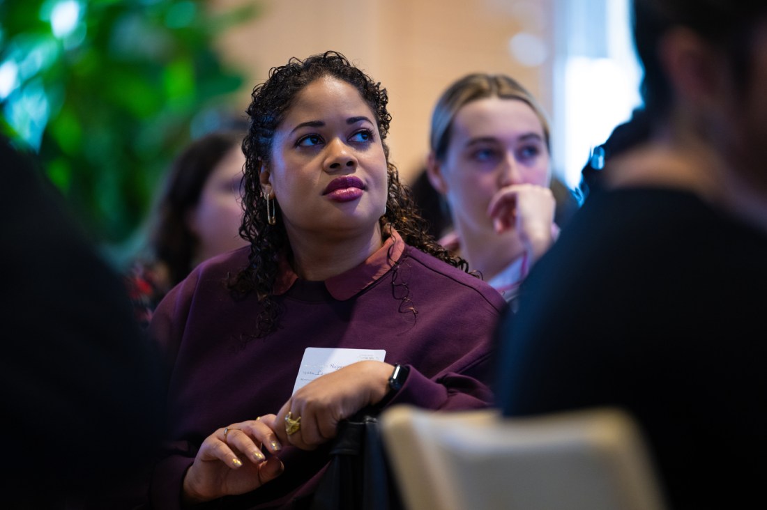 Two women sit in an audience at the Northeastern Social Media Summit, listening intently. 