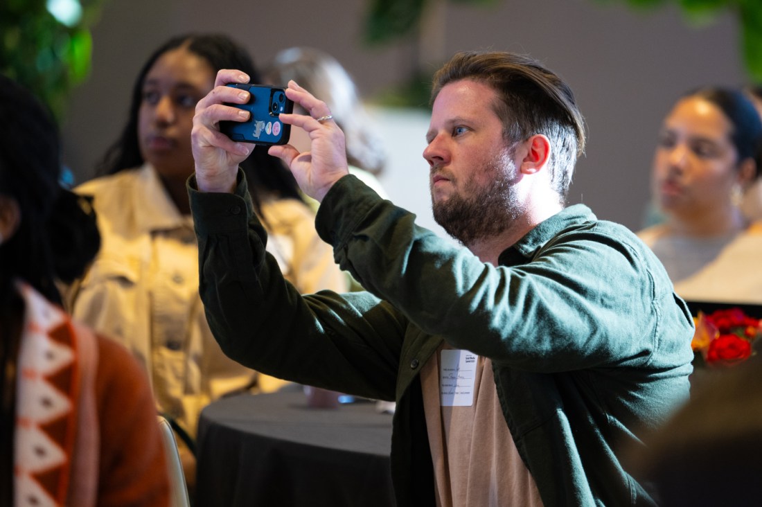 An attendee holds up their phone to take a photo or video during a session at the Northeastern Social Media Summit. 