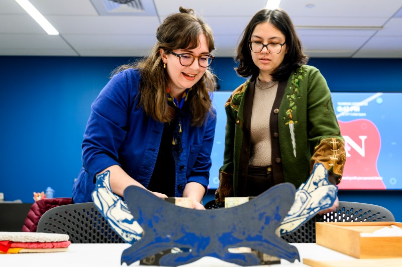 Molly Brown and Julia Lee look at artwork during Snell Library's special event.