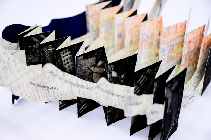 An accordion-fold artist's book with mixed-media pages displayed at Northeastern's Snell Library special collections event.