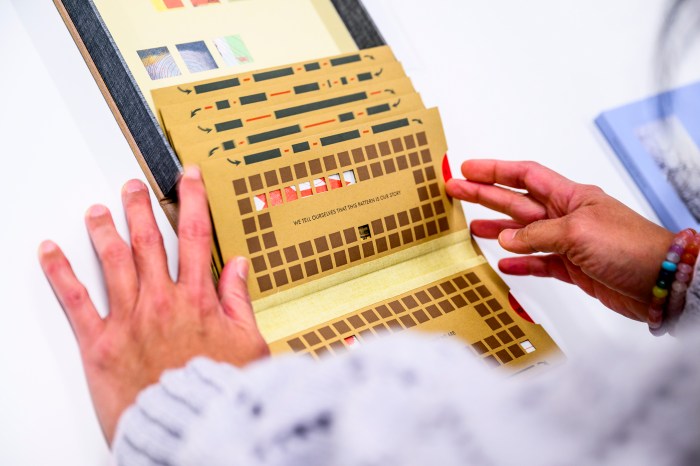 Hands examine a folded accordion-style artist's book with intricate cutout designs.