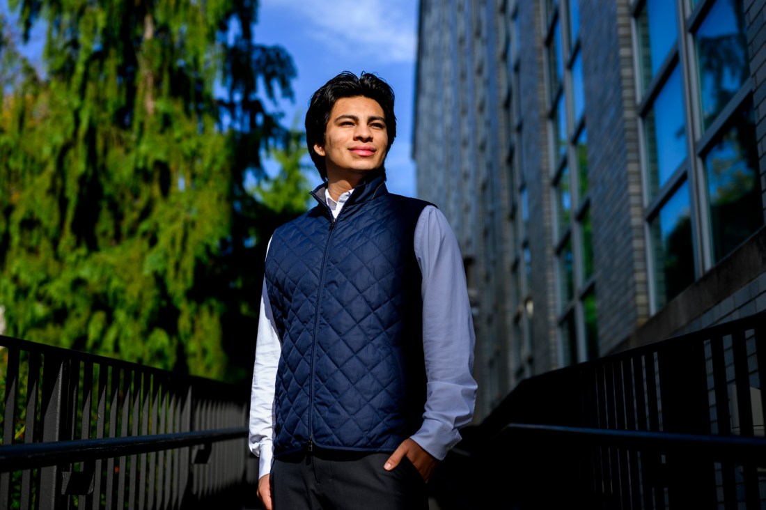 James Elespuru wearing a navy quilted vest and light blue dress shirt standing outside with one hand in his pocket. 