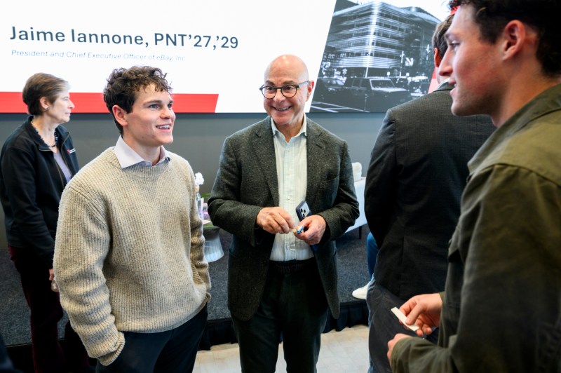 A student in a light sweater speaks while standing next to Joseph E. Aoun at a networking reception following the event.