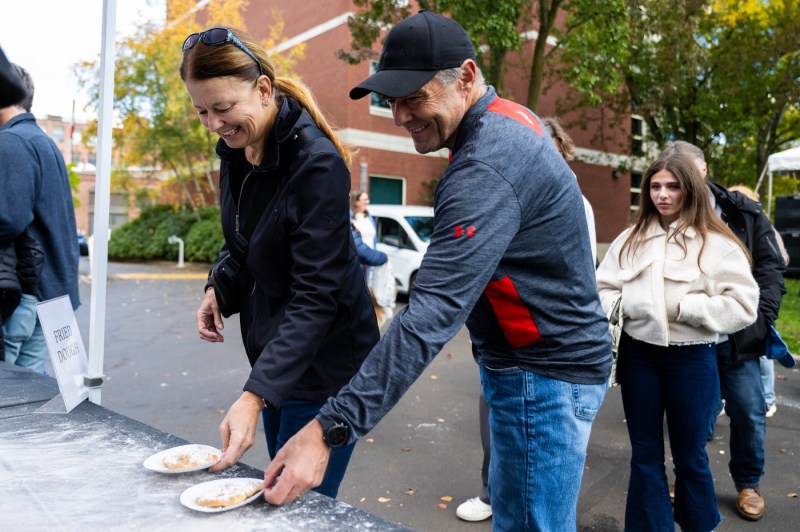 Attendees smile while tossing beanbags at an outdoor game station during Northeastern’s Friends and Family Weekend Fall Festival.