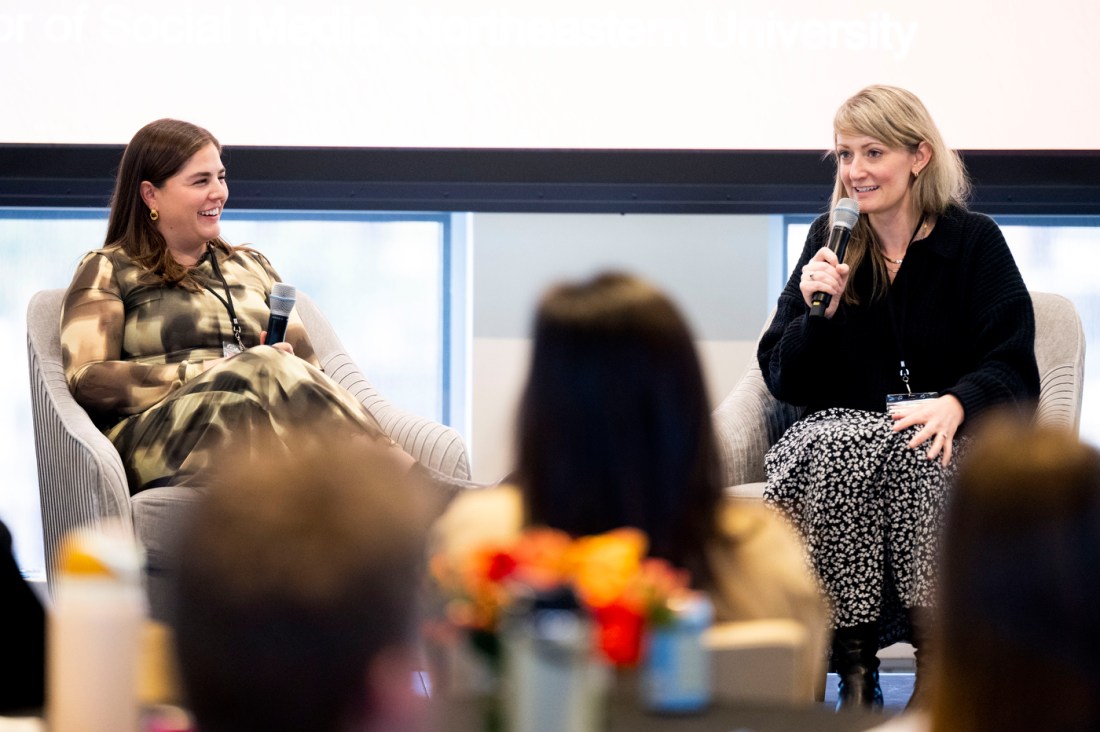 Fernanda Hurtado Ortiz and Jessica Fenerlis sitting on stage speaking into microphones during the Social Media Summit. 