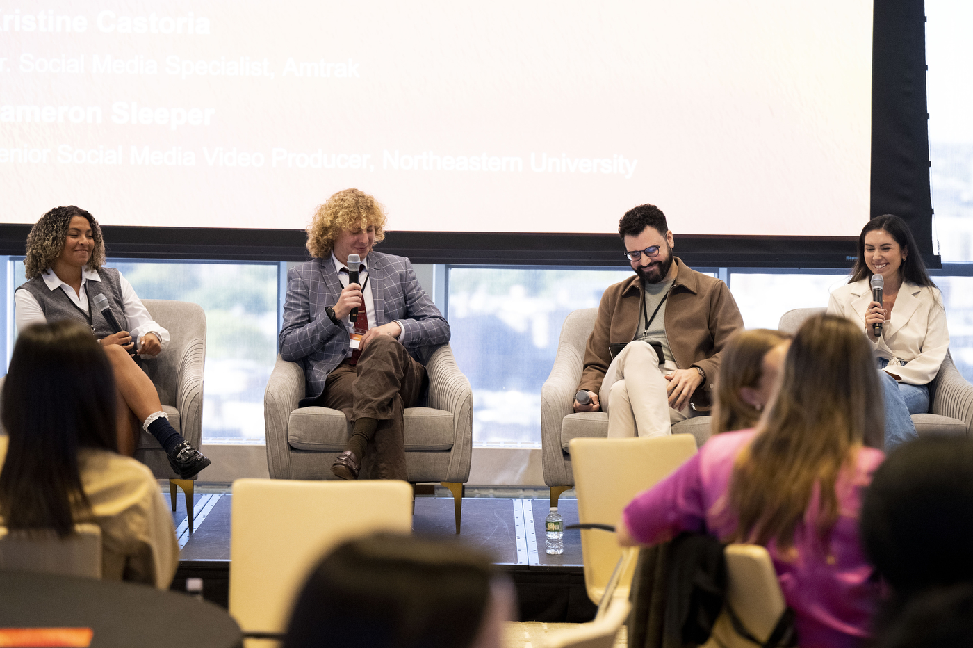 Four panelists sitting on stage holding microphones at the Social Media Summit. 