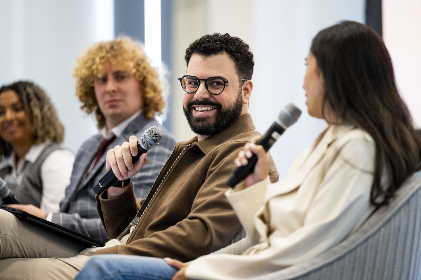 Rachel Vogel, Cameron Sleeper, Diogo Canas, and Kristine Castoria all sitting on stage in grey armchairs and holding microphones. 