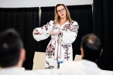 Illena Armstrong, wearing an embroidered white dress, gesturing while speaking at a training event.