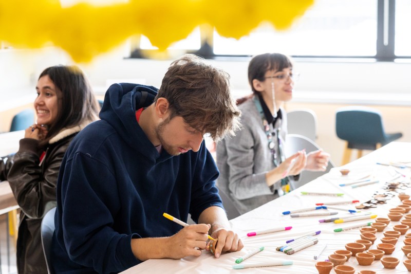 A man in a blue sweatshirt draws henna on his hand. 