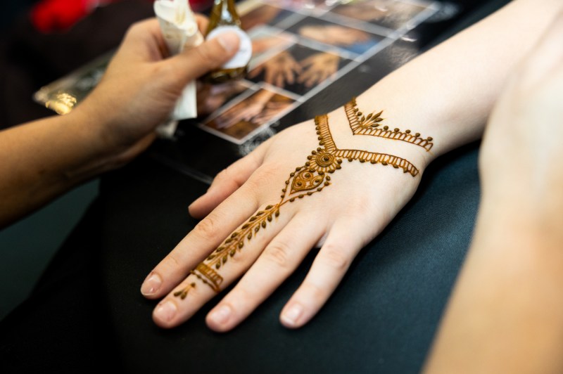 A hand with henna designs rests on a table.