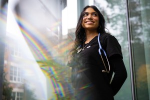 Aishah Daiyan, a Northeastern nursing student, wears a black nursing outfit with a stethoscope.