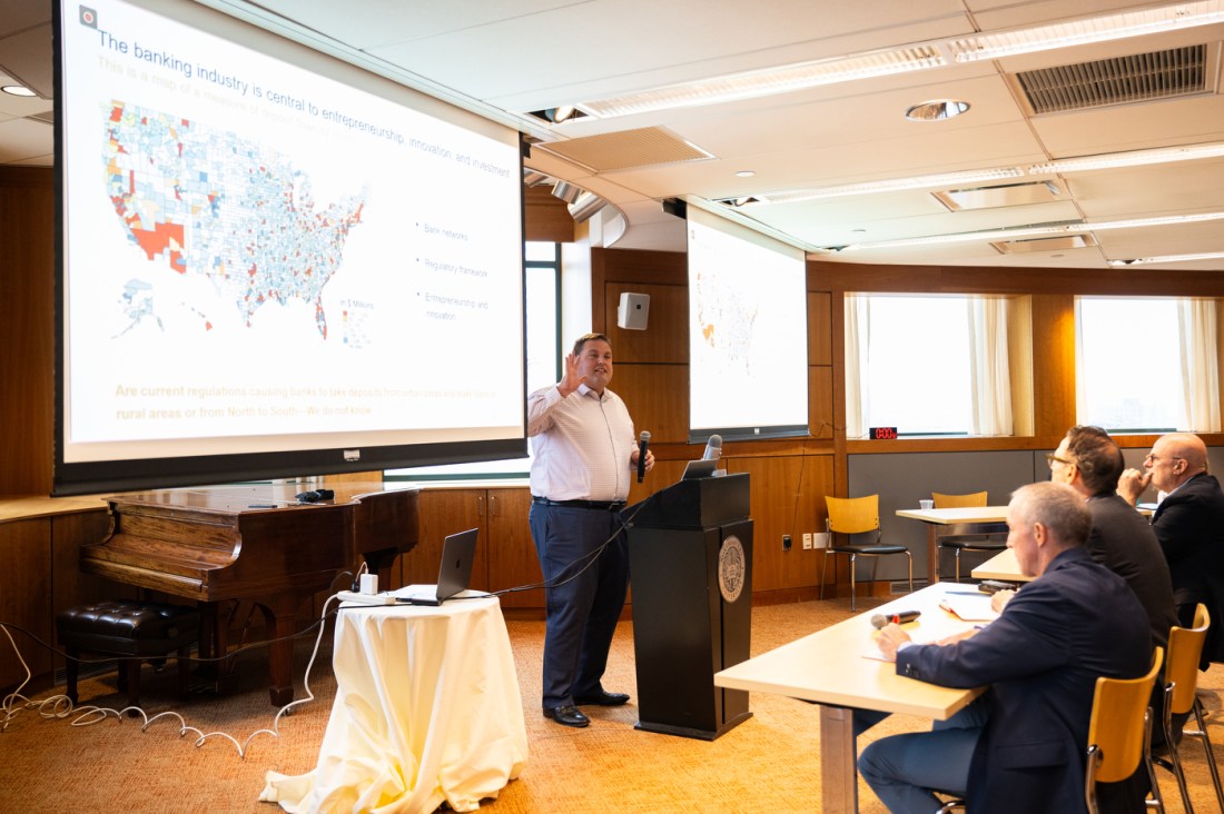 A presenter gestures toward a slide showing a U.S. map and data during a session at DMSB Day at Northeastern University.