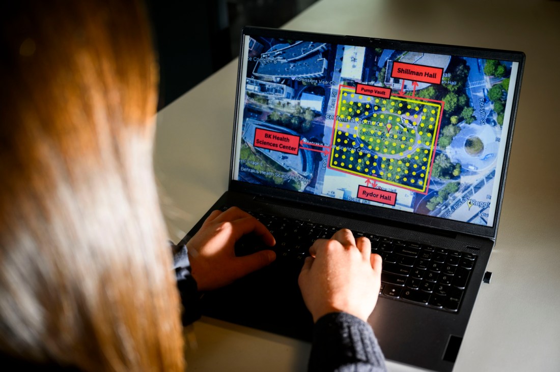 A person with brown hair at work on a laptop, which displays information about a campus project.