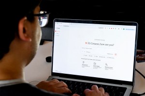 A man with glasses is using a generative AI tool on his laptop.