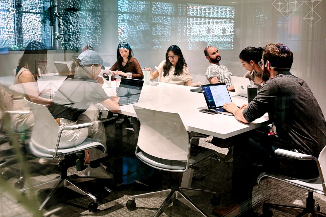 A half dozen students sitting around a conference table working on their laptops.