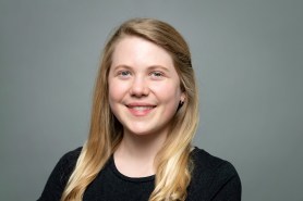Claire Beskin, a young white woman with blonde hair, smiling against a gray backdrop.