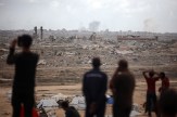 People stand and look at destroyed buildings in Gaza following heavy bombardment, after Israel and Hamas agreed to a ceasefire deal on Oct. 9 to free remaining hostages.