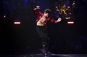 Musician Harry Styles dances on stage with his chest and stomach exposed.