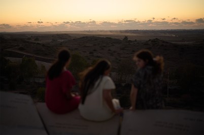 A group of people observing from a distance destroyed buildings in Gaza.