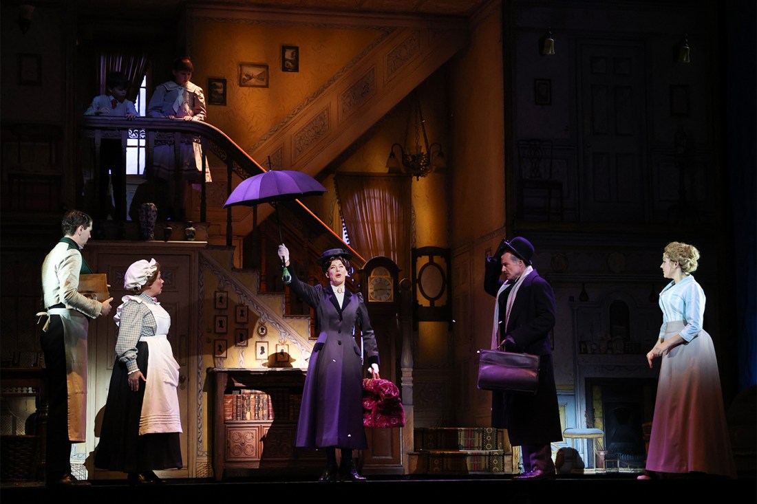 Stefanie Jones as Mary Poppins holds up an umbrella alongside others from the cast on a stage during a media preview of Mary Poppins.