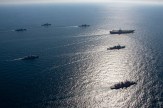 A series of navy ships traversing the open waters.