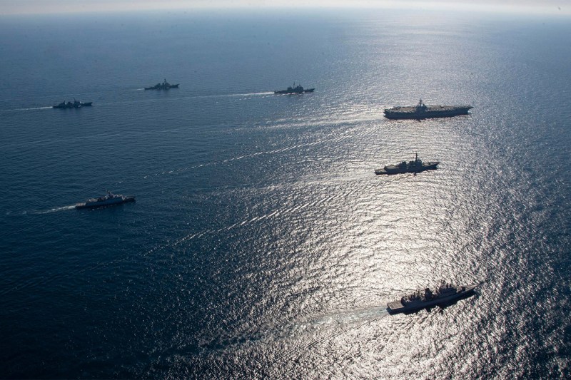 A series of navy ships traversing the open waters.