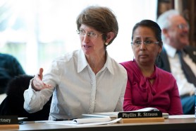 Phyllis Strauss, sitting at a table at the Faculty Senate convention, gesturing while speaking.