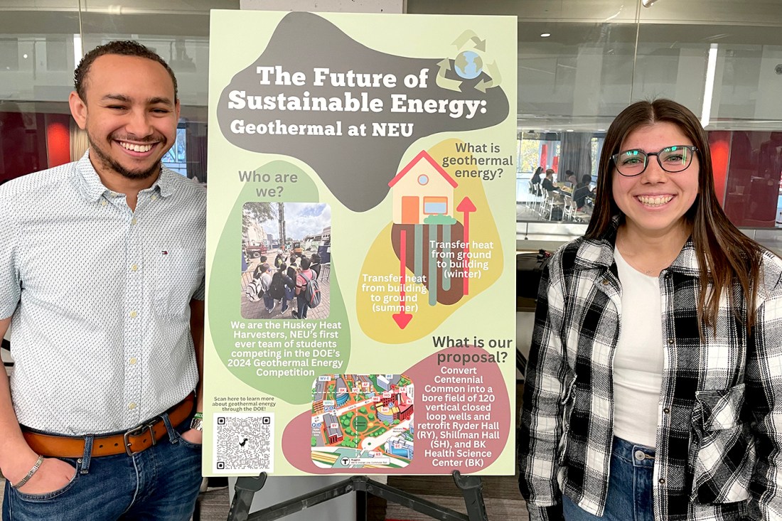 Two students stand beside a poster that displays the text "The Future of Sustainable Energy: Geothermal at NEU."