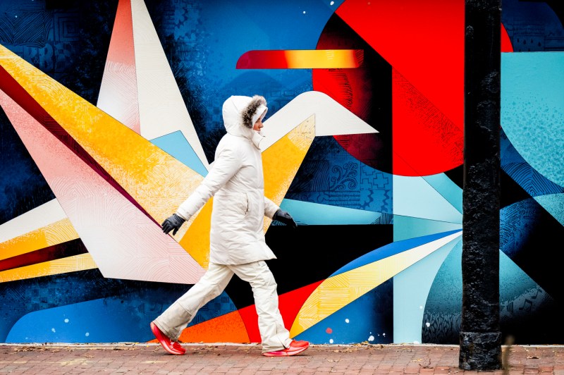 A person walks past a colorful mural. 