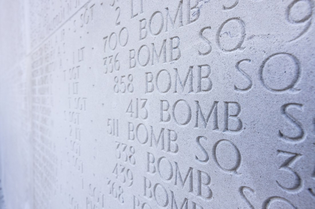 Carved text showing repeated lines of 'BOMB SQ' with numbers at the Cambridge American Cemetary.