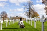 A student looks at rows of white cross markers at the Cambridge American Cemetary.