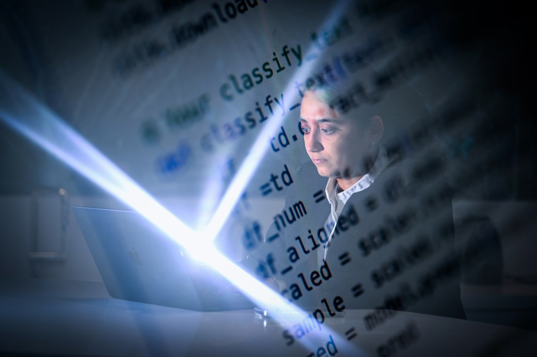 Sohni Rais looking at a laptop screen. Lines of code are overlaid on the image.