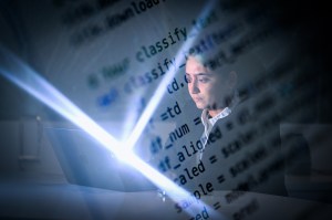 Sohni Rais looking at a laptop screen. Lines of code are overlaid on the image.